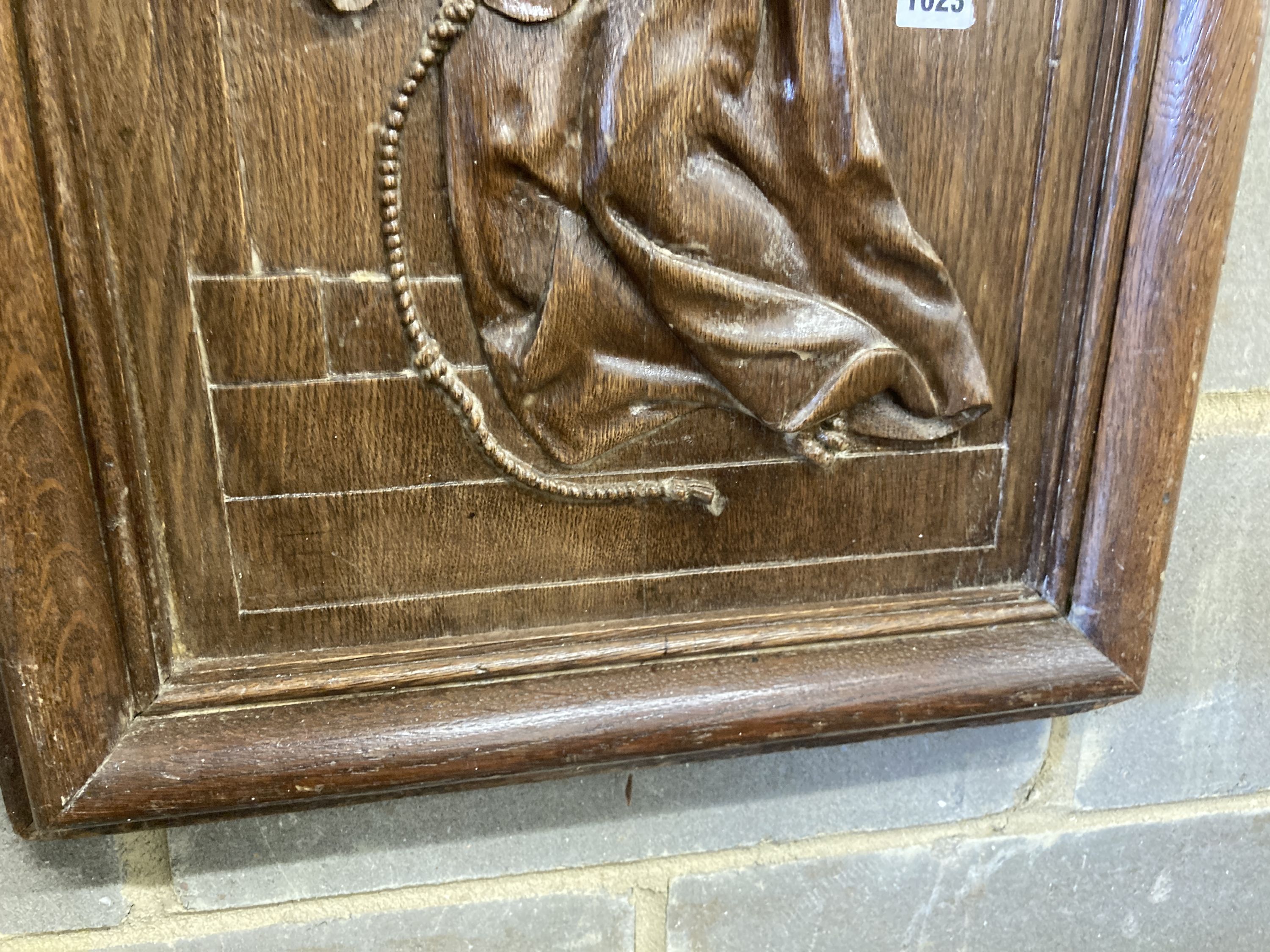 A rectangular carved oak wall panel depicting religious scene